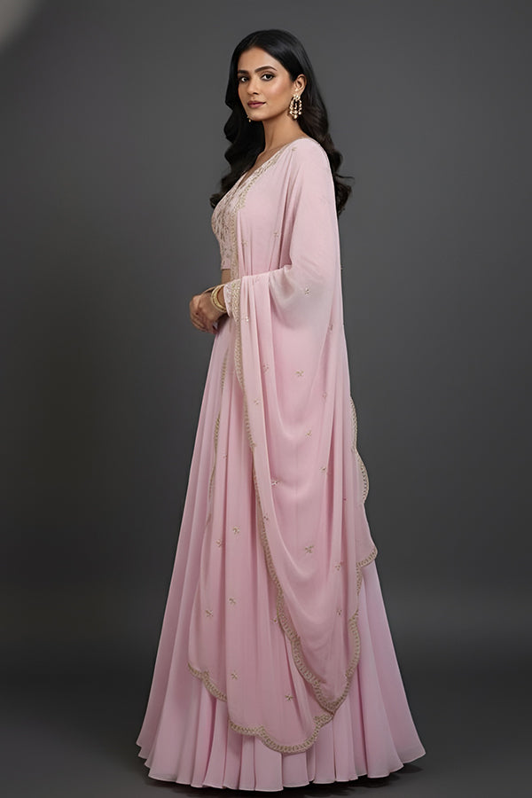 Woman wearing a pink traditional outfit with a matching dupatta on a gray background